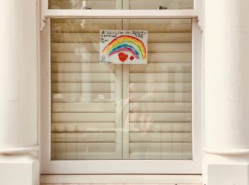 In einer Fensterscheibe ist ein gemalter Regenbogen zu sein. Er symbolisiert Verbundenheit und gibt Trost in der Corona-Pandemie.