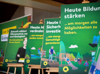 Vier Grüne Plakate zu den Themen Bildung und sozialer Sicherheit sowie ein Kandidatinnenplakat vor dem Großflächenmotiv.
